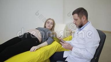 医生把手放在孕妇`肚子上。 怀孕妇女医疗卡上的条目